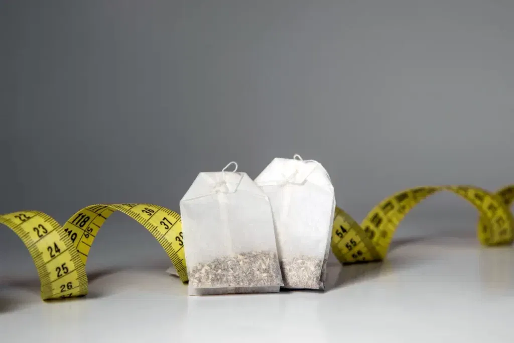 Two caffeine tea bags with yellow inch tape in the background.