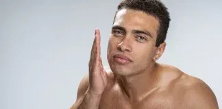 Man applying self tanner on his face.